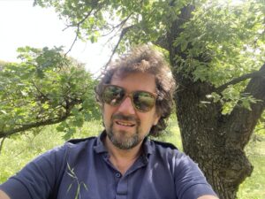 Photo de Nicolas Bermond avec des lunettes de soleil au milieu de la nature verdoyante